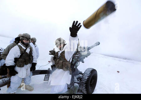 U.S. Army Pfc. Cody Teel, left, watches as Spc. Mohammed Abbas throws an expended 105mm howitzer shell during live-fire training on Joint Base Elmendorf-Richardson, Alaska, Dec. 18, 2013. Teel and Abbas are assigned to the 25th Infantry Division's 2nd Battalion, 377th Parachute Field Artillery Regiment, 4th Infantry Brigade Combat Team, Alaska.  Justin Connaher Stock Photo