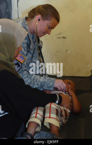 A mother holds her son while U.S. Army Capt.  Kimberly Latham uses her stethoscope to listen to his breathing during medical operations in Hor Al Bosh, Iraq, July 15, 2007.  Latham is a doctor with 115th Brigade Support Battalion out of Camp Taji.  Sgt. Rachel M. Ahner Released Stock Photo