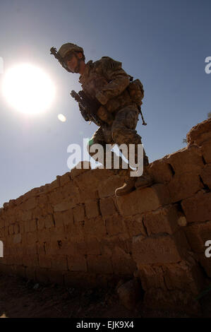 U.S. Army 1st Lt. Travis Plummer, from the 0832 Military Transition Team MiTT, 3rd Heavy Brigade Combat Team, 3rd Infantry Division, prepares to jump off a stone wall while patrolling through Ali Shaheen, Iraq, during a joint clearing operation with Iraqi army soldiers from 3rd Company, 2nd Battalion, 32nd Infantry Brigade, 8th Iraqi Army Division March 7, 2008.  Sgt. Timothy Kingston Stock Photo
