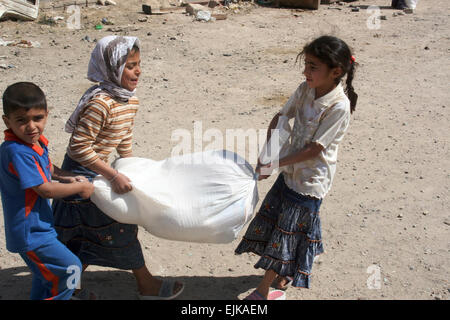 Children carry a bag of food they received from Iraqi police in Fallujah, Iraq, April 2, 2008.  Lance Cpl. Daniel Martin Moman Stock Photo