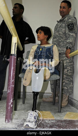 Shiad Abas Aziz and U.S. Army Staff Sgt. Luis Falcon, a squad leader with the 2nd Infantry Division, look on as Shiad is given instructions on how to properly care for her new legs.  Airman 1st Class Andrew Davis      see: /-news/2008/05/12/9102-young-iraqi-girl-recei...  /-news/2008/05/12/9102-young-iraqi-girl-receives-prosthetic-legs/ Stock Photo