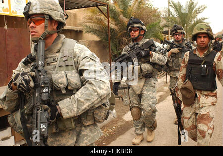 From left, U.S. Army Staff Sgt. Juan Alba, Cpl. Joseph Casiano, Spc. David Tunstall and an Iraqi National Police officer conduct a combined cordon and search foot patrol at a market in Ghazaliya, Iraq, March 23, 2007. The Soldiers are from Black Hawk Company, 1st Battalion, 23rd Infantry Regiment, 3rd Brigade Combat Team, 2nd Infantry Division.  Sgt. Tierney Nowland, U.S. Army. Stock Photo