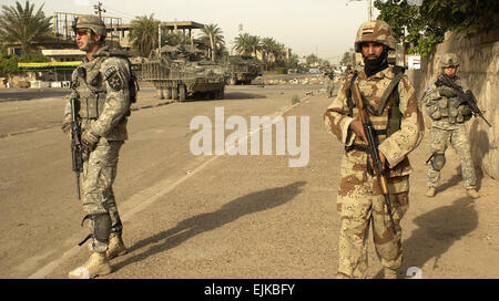 U.S. Army Staff Sgt. Brian Piehler, Spc. Allison Freckles and an Iraqi army soldier move to their next objective on foot during a combined cordon and search in Ameriyah, Iraq, April 25, 2007. The U.S. Soldiers are assigned to Charlie Company, 1st Battalion, 23rd Infantry Regiment, 3rd Stryker Brigade Combat Team, 2nd Infantry Division.   Sgt. Tierney Nowland Stock Photo