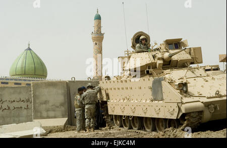 U.S. Army Soldiers with 2nd Battalion, 7th Army Infantry Brigade provide security from an M1A1 Bradley tank in Hit, Iraq, during a claims payment April 29, 2007, during a claims payment visit by U.S. Marines and Navy Sailors with Regimental Combat Team 2's legal department.  Sgt. James R. Richardson Stock Photo