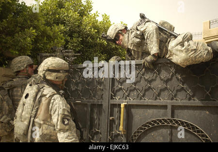 A U.S. Army Soldier from Alpha Company, 2nd Battalion, 3rd Infantry Regiment jumps over a gate to unlock it to search a house in Rashid, Iraq, June 2, 2007.  Sgt. Tierney Nowland Stock Photo