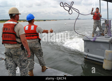 Pfc. Juan Guebara, right, a watercraft engineer assigned to the 7th Sustainment Brigade, tosses a line to two soldiers on the main causeway during a Joint Logistics Over the Shore exercise at Fort Story, Va., Aug. 21. The JLOTS exercises are performed around the world in joint and coalition environments. Operations involve loading and unloading of ships without the benefit of deep draft-capable, fixed port facilities. This exercise involves both U.S. Army and Navy personnel interacting to accomplish the mission. Stock Photo