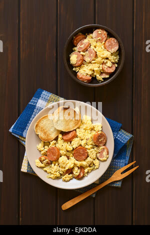 Overhead shot of scrambled eggs made with chorizo slices and onion on plate with toasted baguette slices Stock Photo