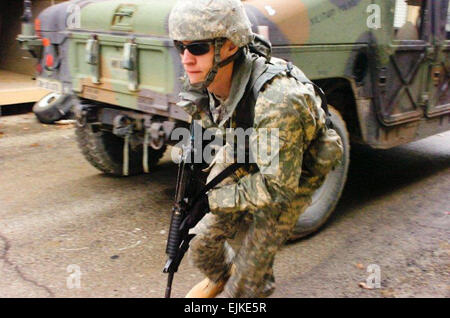 Spc. Dustin Schultz, a Seymour, Ind., native and military policeman with the 384th Military Police Company, runs from one vehicle to another under enemy fire during an enemy ambush to ensure all State Department officials have been safely loaded into vehicles for evacuation.  The 384th Soldiers acted as security forces for the State Department as they went through Foreign Service Institute Training at the Muscatatuck Urban Training Center Feb 13-18. Stock Photo