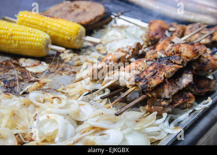 Barbecued chicken kebabs on skewers, corn on the cob and onions Stock Photo