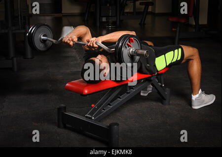 Young man doing arms bench french press workout in gym Stock Photo