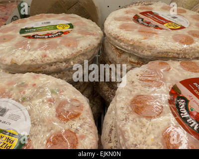 Packages of frozen pizza are stacked in a supermarket freezer section. Stock Photo