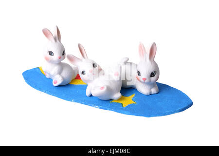 Three little rabbits playing surfboard on white background. Stock Photo