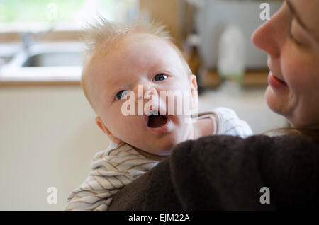 Yawning 14-week-old baby boy on his mother's shoulder. Stock Photo