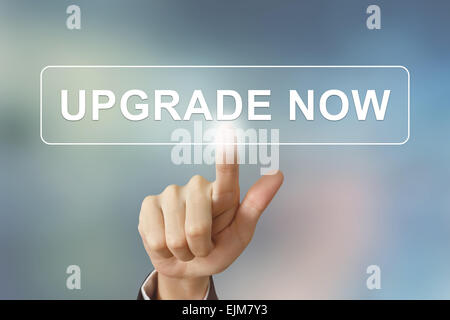 business hand pushing upgrade now button on blurred background Stock Photo