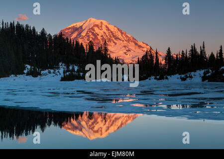 Mount Rainier in evening light reflected in partially frozen Eunice Lake, Mount Rainier National Park, Washington, USA. Stock Photo