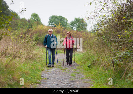 Senior couple Nordic walking on rocky trail in the nature. Stock Photo