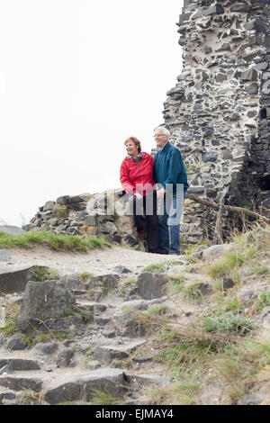 Happy senior couple hiking and resting on rocky trail outdoors. Stock Photo