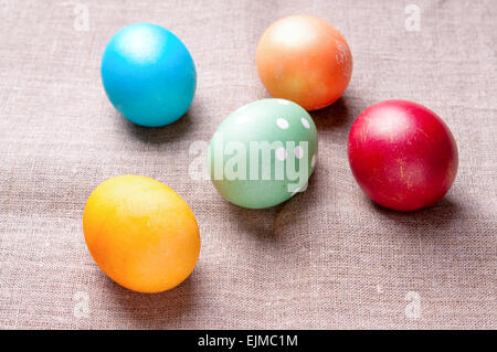 Group of colorful Easter eggs lying on linen fabric cloth close up Stock Photo
