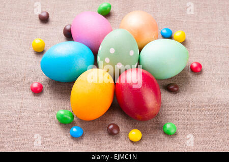 Group of colorful Easter eggs and colored candies lying on linen fabric cloth close up Stock Photo