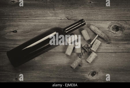 Vintage concept of antique corkscrew, used corks, and wine bottle on rustic wooden boards. Top view horizontal format. Stock Photo