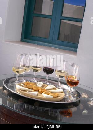 wine tasting alfresco situation with selection of red and white wines with cheese and dry biscuits on barrel end with corks with wine bodega behind Stock Photo