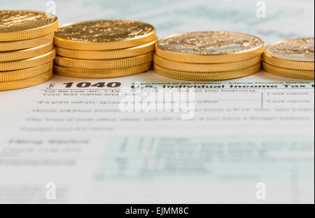 Solid gold eagle coins on USA tax form 1040 for year 2014  illustrating payment of taxes on forms for the IRS Stock Photo