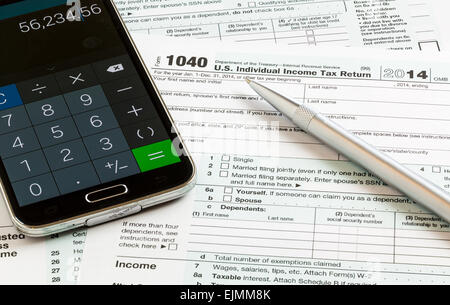 USA tax form 1040 for year 2014 with a pen and calculator app on smartphone illustrating completion of tax forms for the IRS Stock Photo