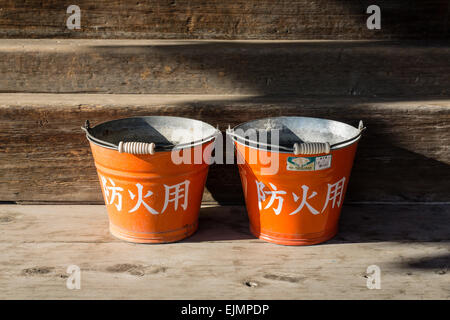Two old orange Japanese fire buckets at a Buddhist temple in Nara, Japan Stock Photo
