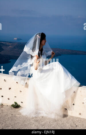 Chinese Girl wearing a traditional wedding dress and veil posing for pre-wedding photos, Firostefani, Santorini (Thera), Greece. Stock Photo