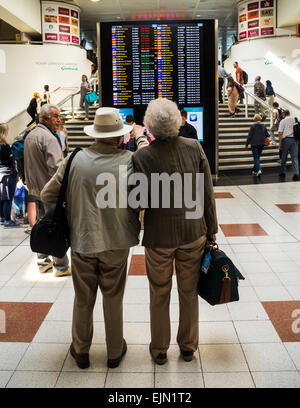 Senior couple checking the flight board at Gatwick Airport, north terminal, West Sussex, England. Stock Photo