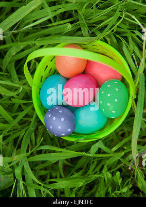 Plastic basket full of Easter eggs in the green grass Stock Photo