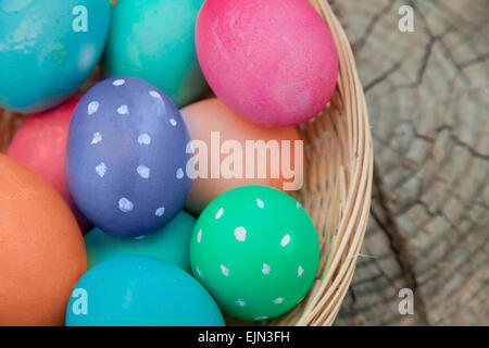 Closeup on the colorful eggs in an Easter nest sitting on a tree stump Stock Photo