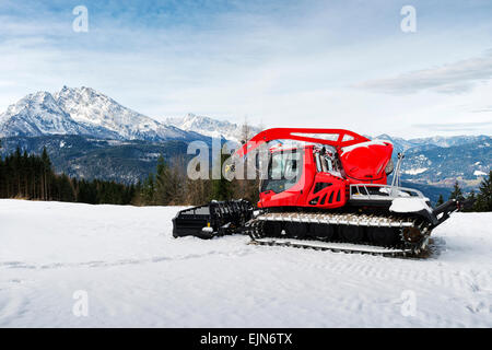 Red machine for skiing slope preparations in alps at background of mount Watzmann, Germany. Stock Photo