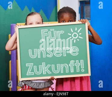 Children holding chalkboard with German slogan 'Fuer unsere Zukunft' (For our future) Stock Photo