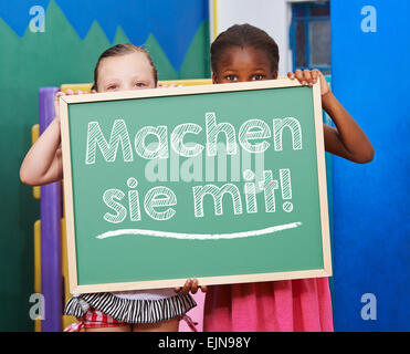 Two children holding a chalkboard with German slogan 'Machen sie mit!' (Join us!) Stock Photo