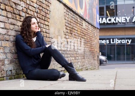 young woman sitting on the pavement thinking Stock Photo