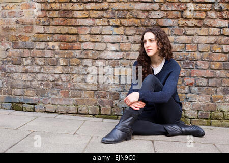 young woman sitting on the pavement Stock Photo