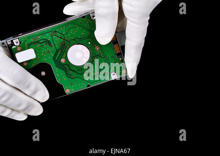Computer hard drive hand held with white gloves isolated on black Stock Photo
