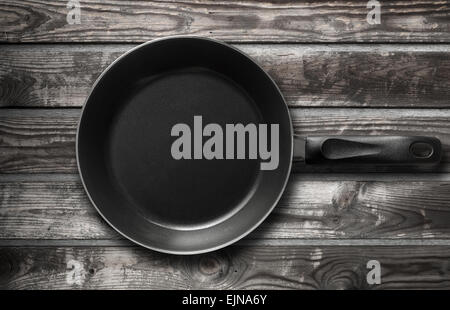 Empty black frying pan stands on old dark wooden table background Stock Photo