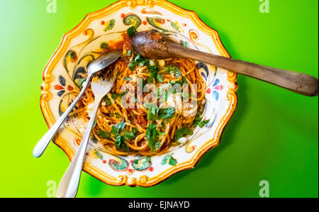 Spaghetti with sardines and olives in ornate Italian bowl on green table, a Sicilian dish Stock Photo