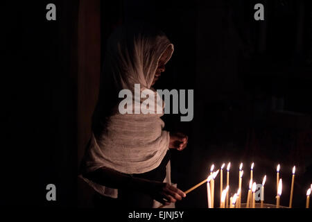 An Ethiopian Orthodox Christian pilgrim lights candles inside the Church of the Holy Sepulchre, in the old city of Jerusalem Israel Stock Photo