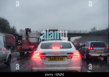 dreary wet rush hour journey standstill on motorway carriage stationary cars lorries with tail rear brake lights low visibility Stock Photo