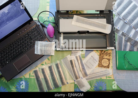 Laptop film scanner and negatives on a table being scanned and transfered to a computer for printing. Stock Photo