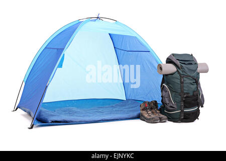 Studio shot of a blue tent, a green rucksack and a pair of boots left next to the tent isolated on white background Stock Photo