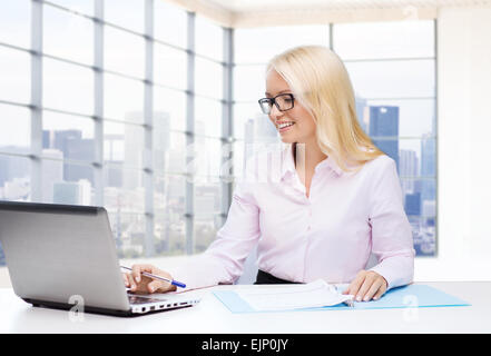 smiling businesswoman reading papers in office Stock Photo