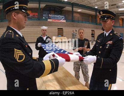 From left, Staff Sgt. Travis Hackey, North Dakota Army National Guard, U.S. Navy Machinist's Mate 2nd Class Marion Parmar, and Spc. Kacey Krueger, North Dakota Army National Guard, begin folding an American flag during military funeral honor team training at the Armed Forces Reserve Center, Fargo, N.D., Aug. 17, 2007.   Senior Master Sgt. David H. Lipp Stock Photo