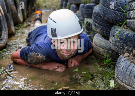 Teenage boy crawling in the mud on a assault course. England. UK Stock Photo