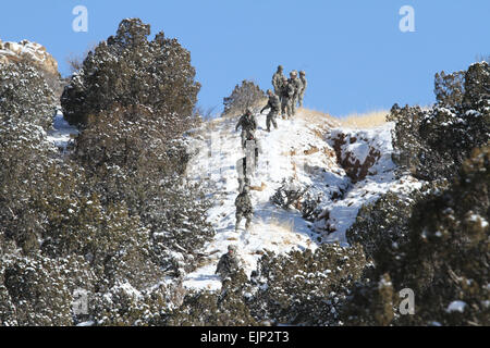 FORT CARSON, Colo. – Paratroopers from Company C, 1st Battalion, 505th Parachute Infantry Regiment, 3rd Brigade Combat Team, 82nd Airborne Division, Fort Bragg, N.C., climb over a hill in order to secure an airfield near Fort Carson's Camp Red Devil training area, Feb. 6, 2014, and defend it from opposing forces from the 1st Battalion, 8th Infantry Regiment, 3rd Armored Brigade Combat Team, 4th Infantry Division, during a joint deployment readiness exercise. The Soldiers were conducting the exercise with Soldiers from Company A, 1st Bn., 68th Armor Regiment, 3rd Armored Brigade Combat Team, 4t Stock Photo