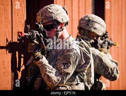 Soldiers of the Massachusetts National Guard, 181st Infantry Regiment provide security while clearing room-to-room at the urban warfare range, Camp Atterbury Joint Maneuver Training Center, Ind., on August 27, 2010.  Roughly 600 soldiers of the 181st are deploying to Afghanistan as part of the largest deployment the Massachusetts Guard has seen since World War II.   John Crosby, U.S. Army.  Released Stock Photo