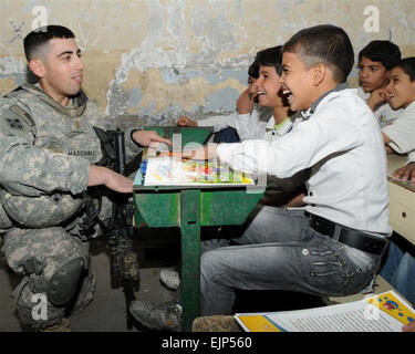 2nd Lt. Joseph Marshall, a native of Boyers, Pa. and the 2nd platoon leader with 1st Battalion, 68th Armored Regiment, 3rd Brigade, 4th Infantry Division, enjoys a moment of laughter with Iraqi children from Al Fatih Al Mubien Primary School in Al Zharnar District, Basra, as part of the Iraqi Army's IA civic action project. The civil military mission, advised and assisted by United States Division-South Soldiers for the IA in establishing community relationships with its people. Stock Photo